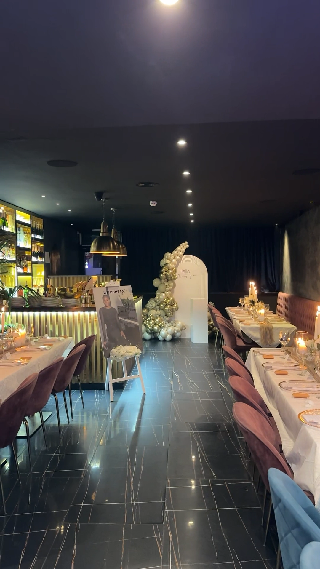 Birthday dinner setup with gold balloon arch and candlelit tables
